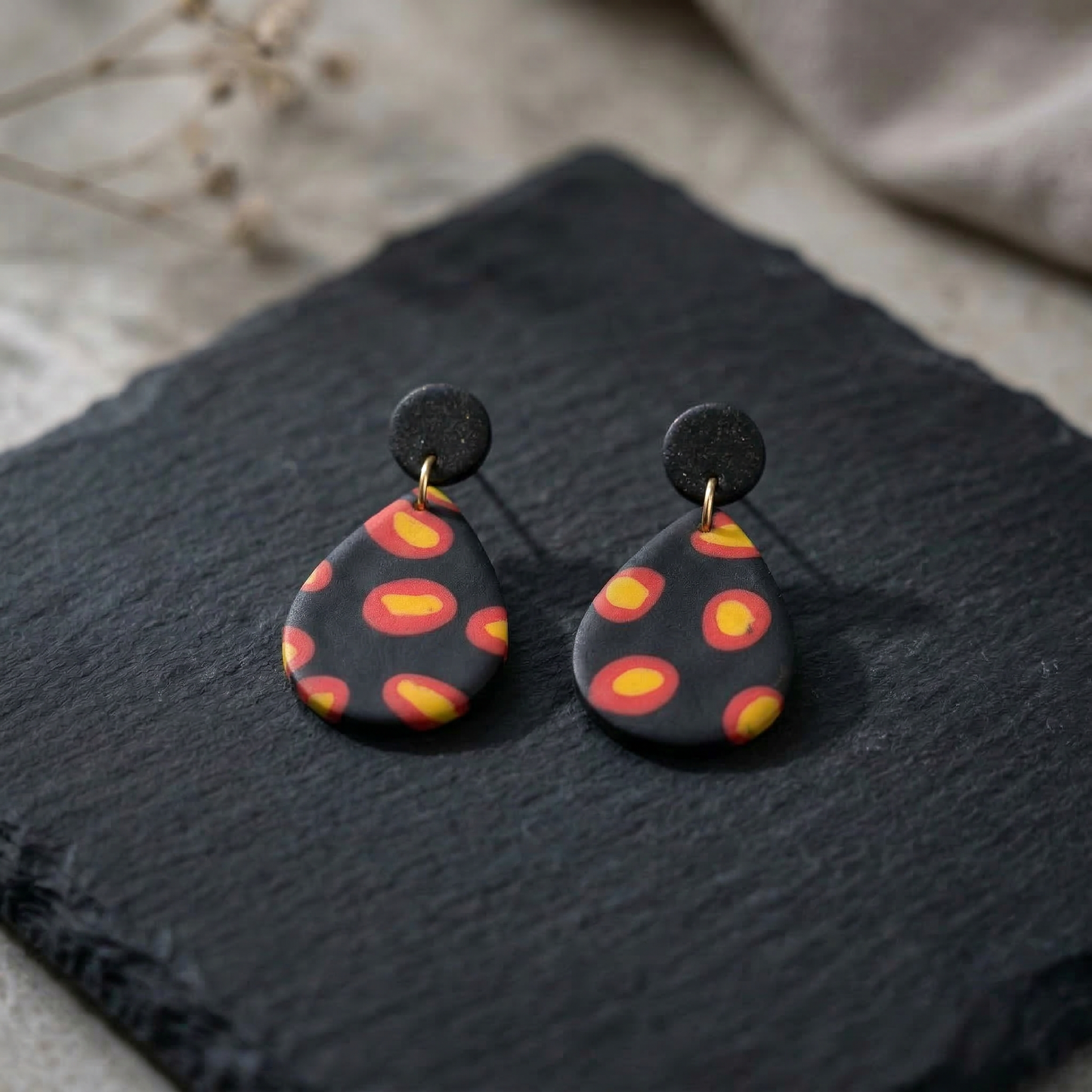 Feuerpunkt – Tropfenförmige Statement-Ohrringe in Schwarz mit leuchtendem Flammenmuster