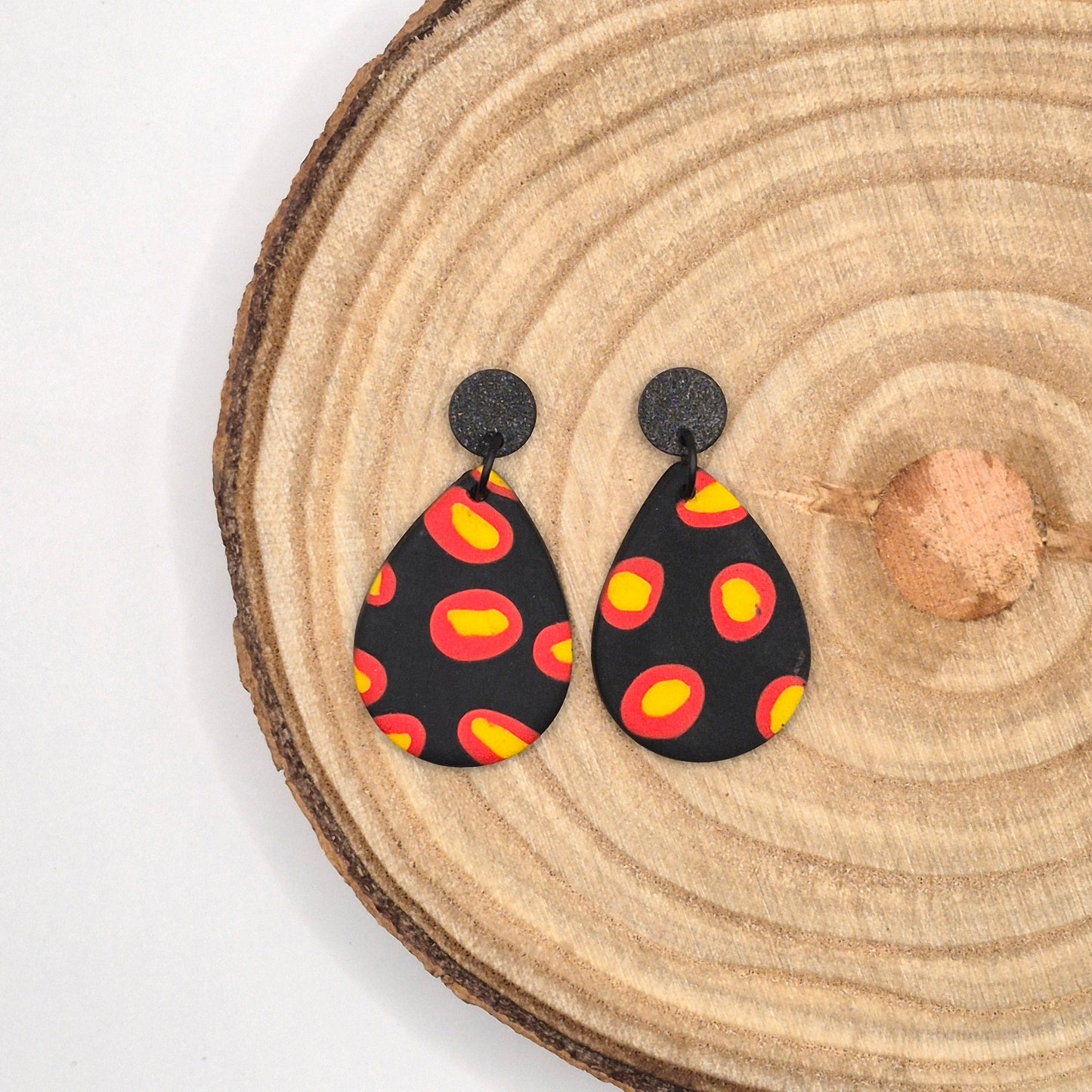 Feuerpunkt – Tropfenförmige Statement-Ohrringe in Schwarz mit leuchtendem Flammenmuster