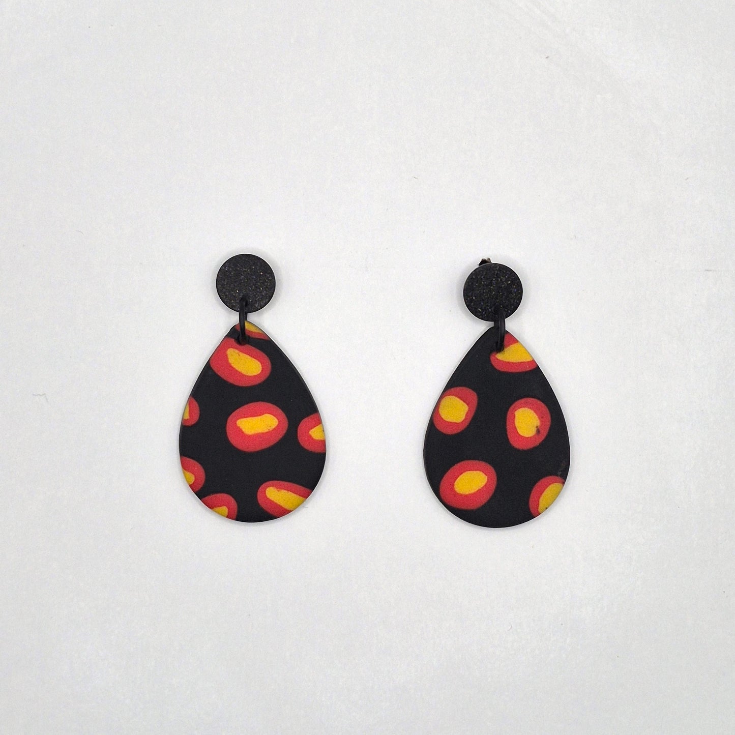 Feuerpunkt – Tropfenförmige Statement-Ohrringe in Schwarz mit leuchtendem Flammenmuster